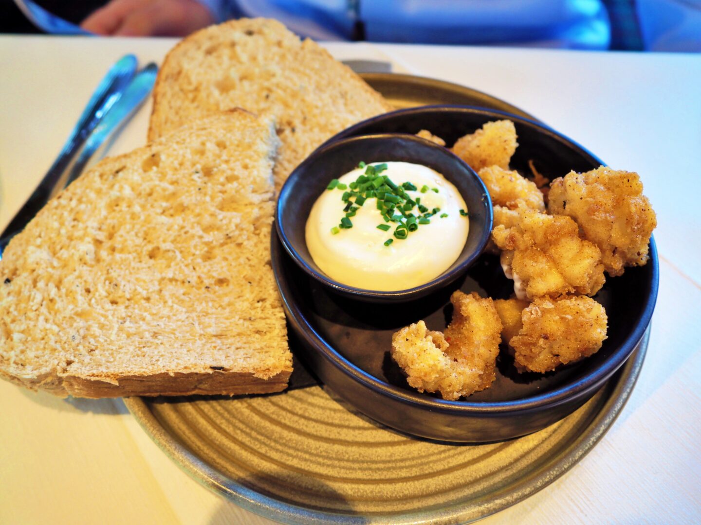 Bread on a plate next to a small dish of lemon aioli and squid