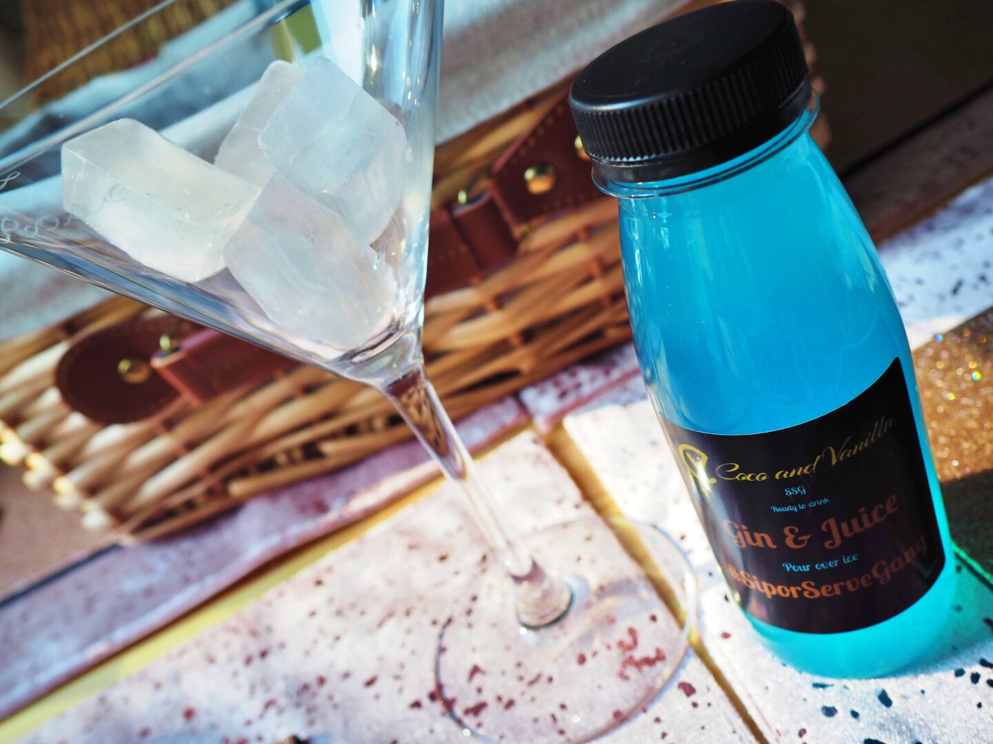 A cocktail next to a bottle with a blue cocktail inside