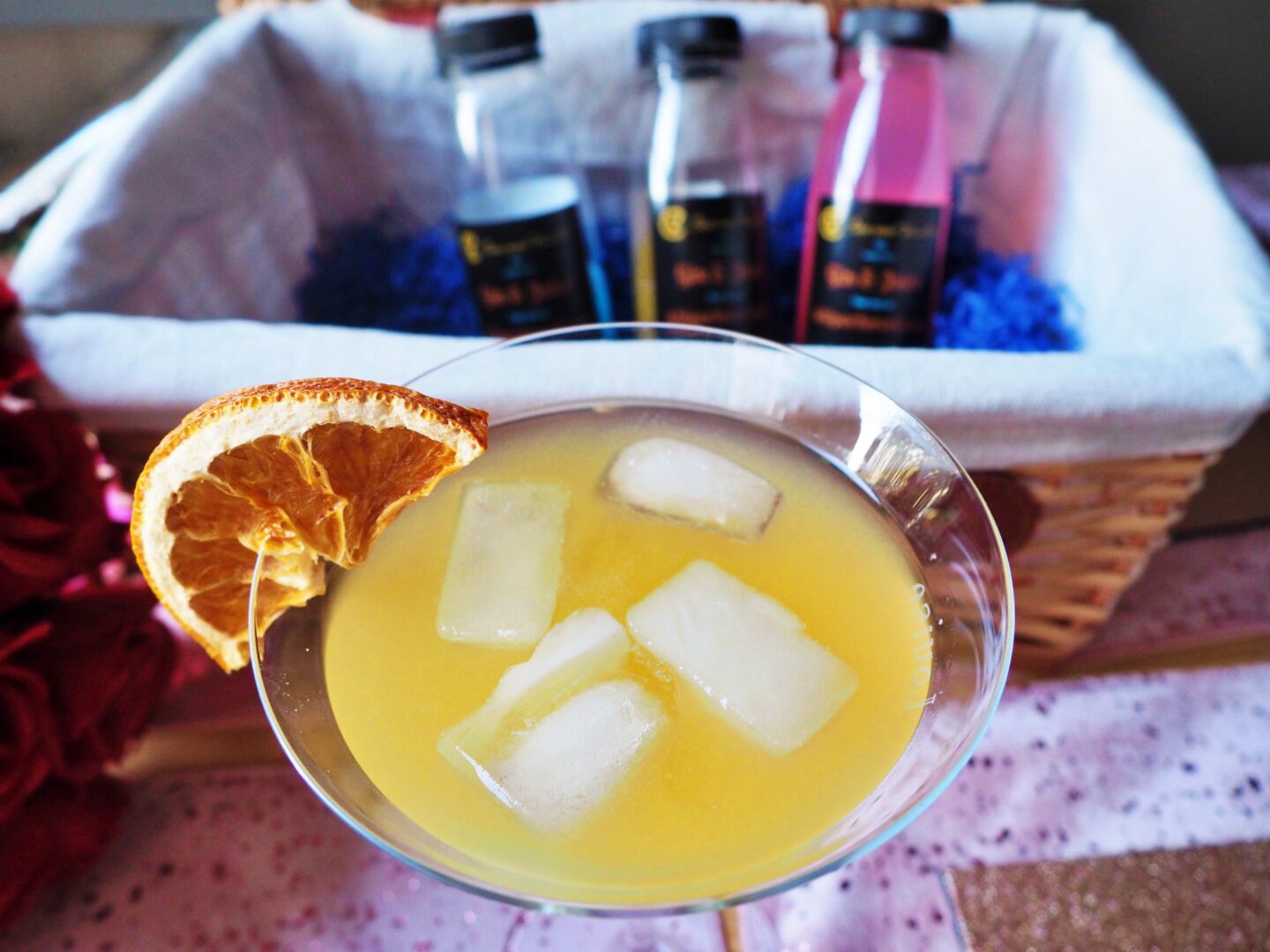 A cocktail glass containing a yellow cocktail with ice