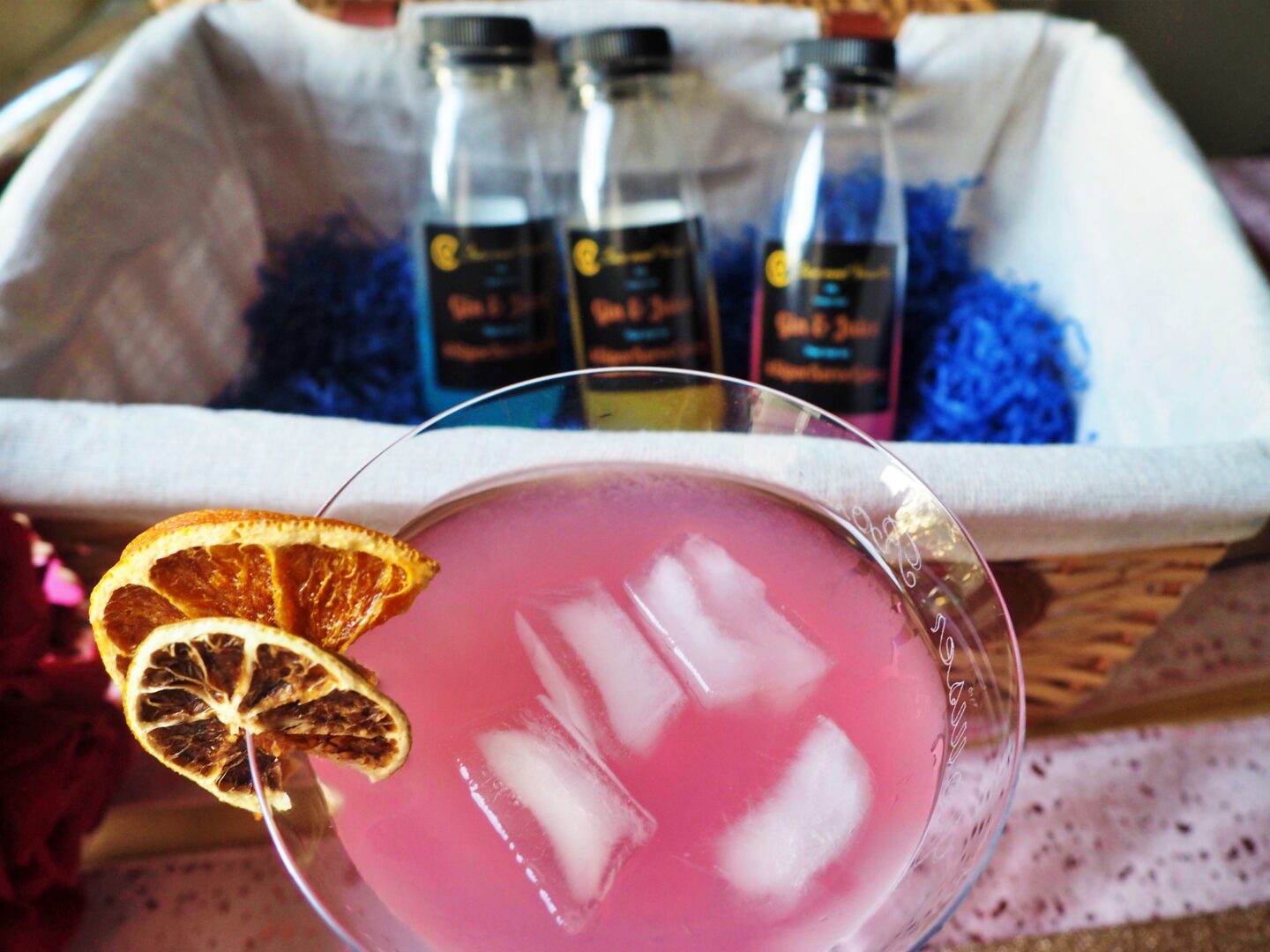 A cocktail glass containing a pink cocktail with ice