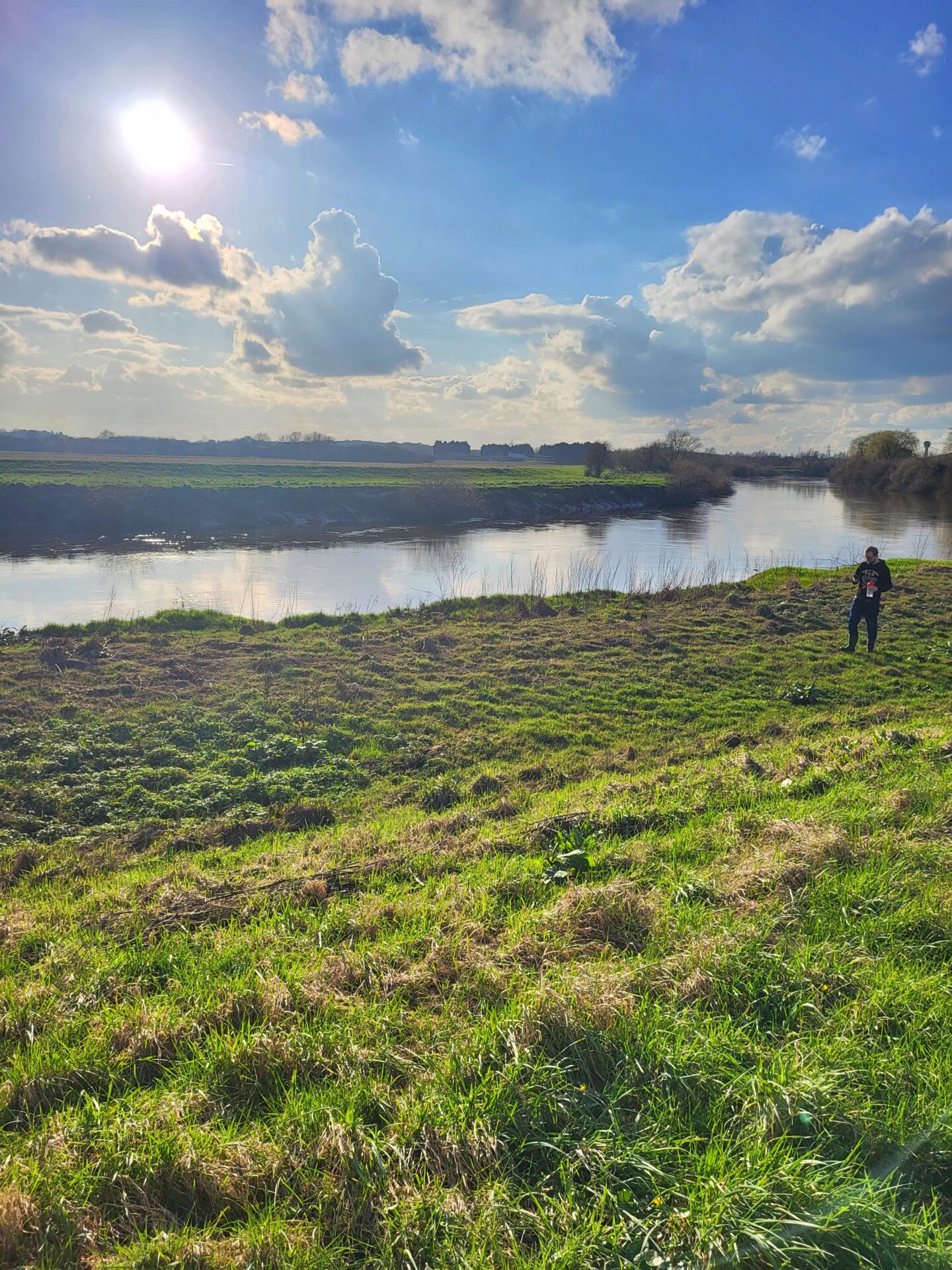 Image shows a scene by the river with fields. My fiancé is on the right hand side of the image in the distance.