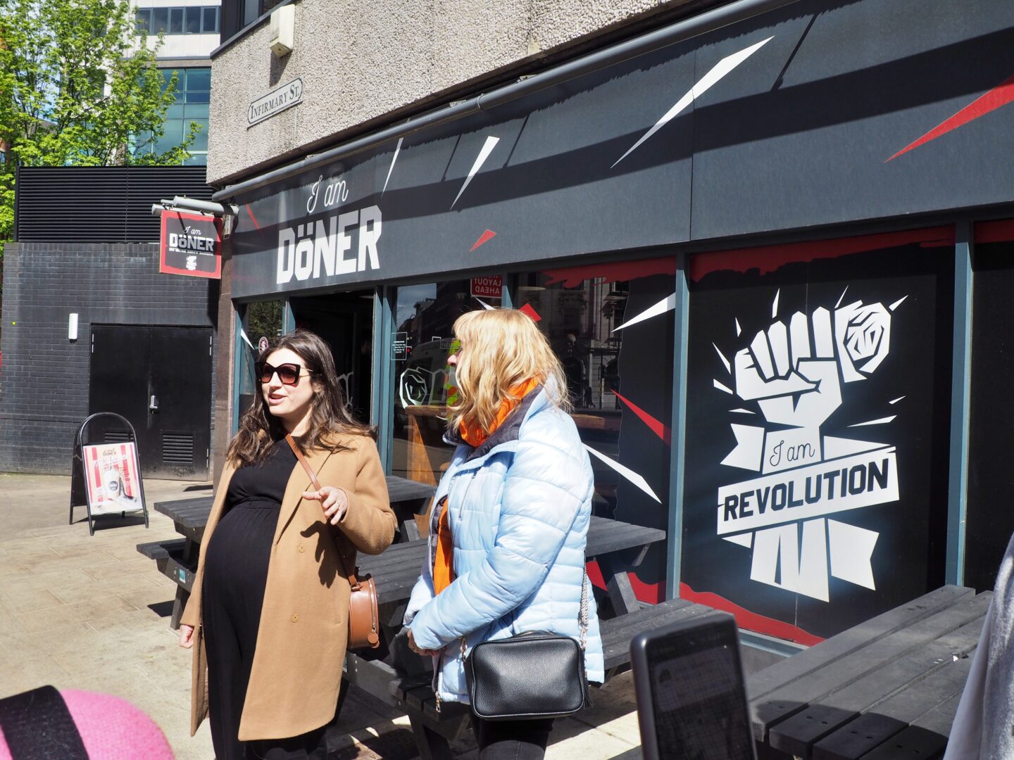 The photo shows Ellen and Lynda from Leeds Food Tours stood in front of IAMDONER in Leeds, talking to the group.
