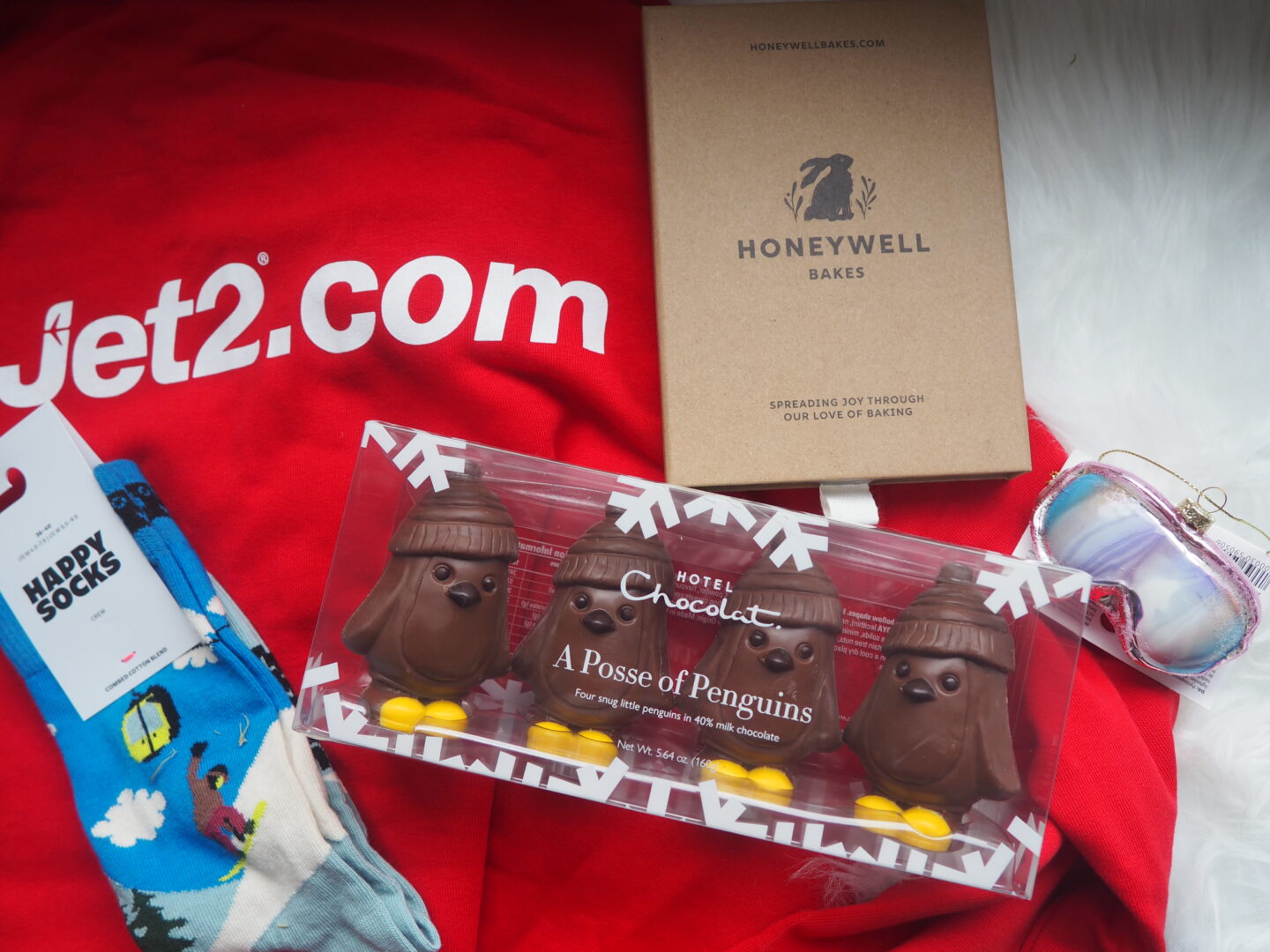 Content from the Jet2 goodie bag, including a Jet2 hoodie, ski themed socks, a Christmas tree decoration, Hotel Chocolate penguins and a box with Jet2 themed gingerbread biscuits.