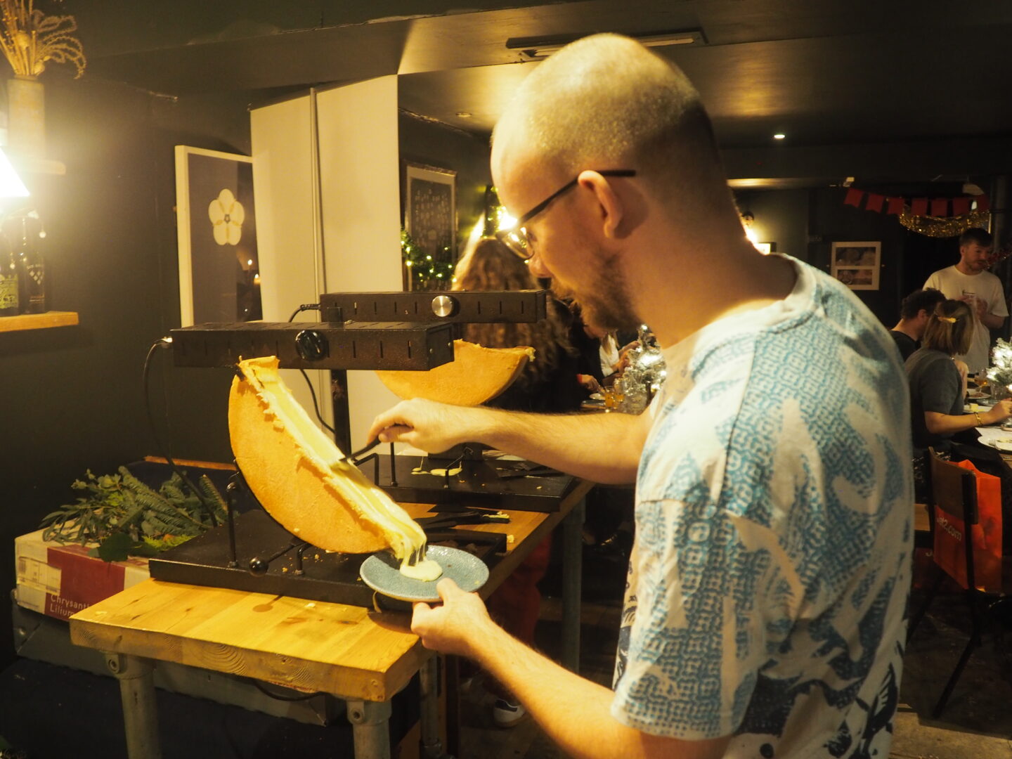 Tom, my husband, holding his plate up to the Cheese Melter Raclette and scraping melted cheese onto his plate.