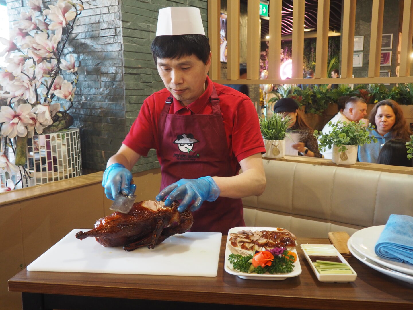 A staff member at Panda Mami York carving duck for duck pancakes.