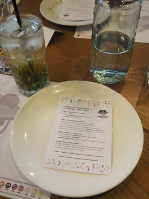 A mocktail on the table at Panda Mami York, next to a plate which includes an event itinerary. 